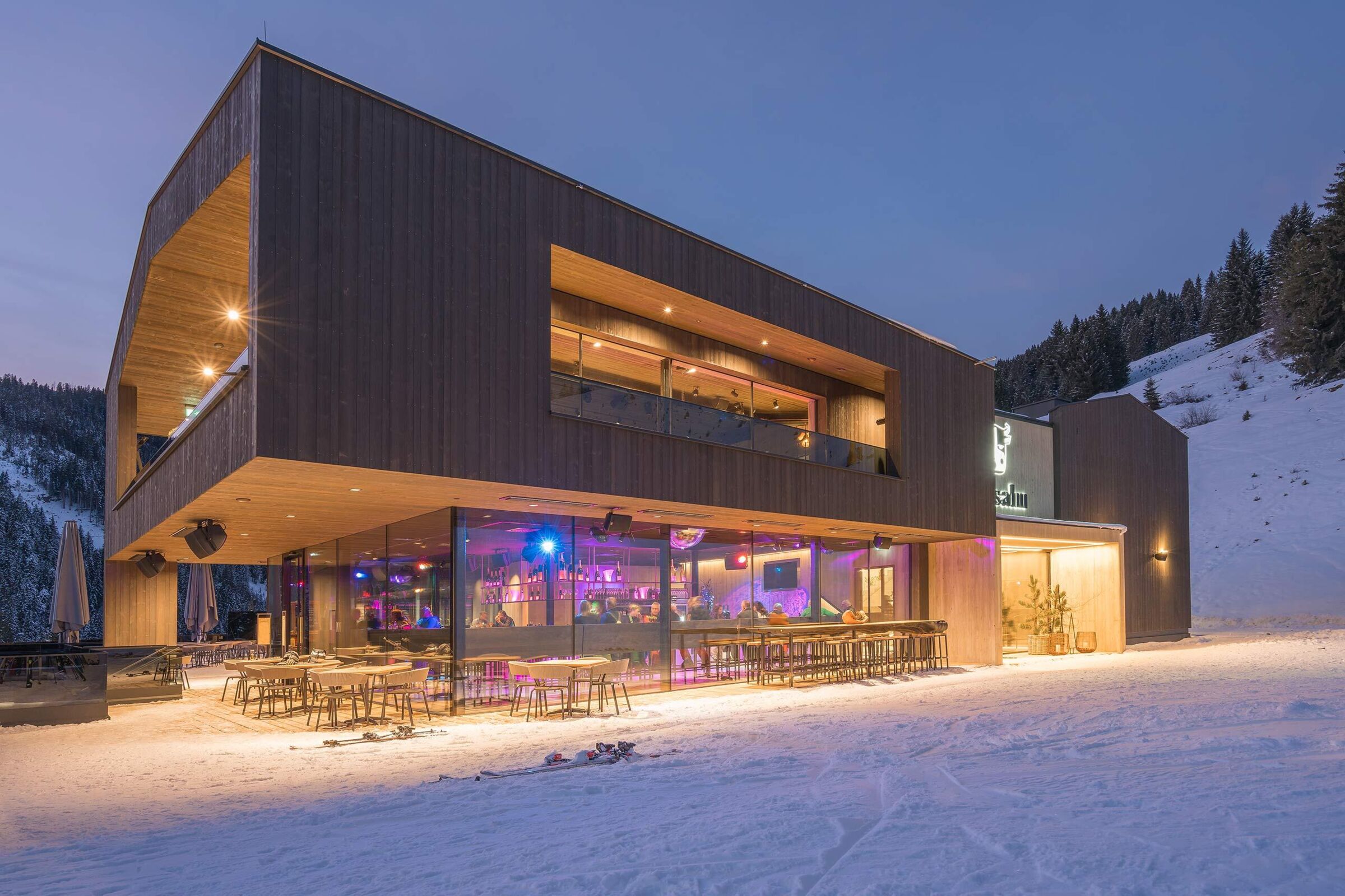 Der Außenbereich der Maisalm in der Nacht im Schnee mit bunter Beleuchtung