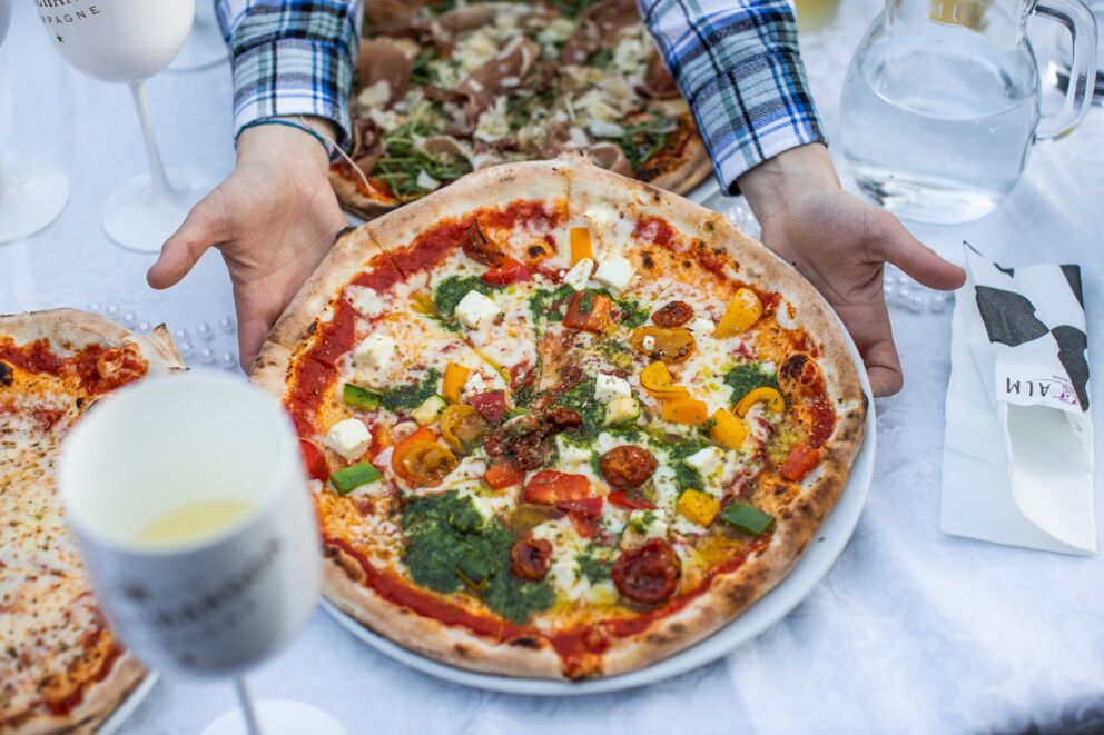 Maisalms Holzofenpizza wird auf einem gedecktem Tisch serviert